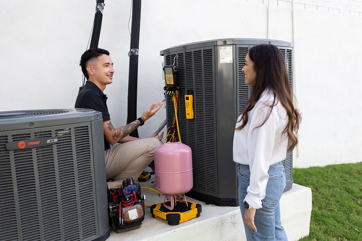 Homeowner reviewing a newly installed HVAC replacement unit with a contractor.